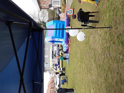 Community fun day with residents enjoying ice cream van and bouncy castle.