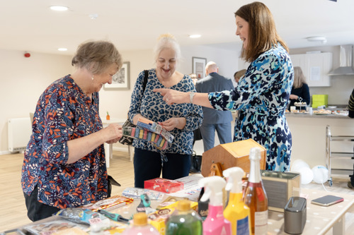 Three ladies laughing and chatting over a prize.