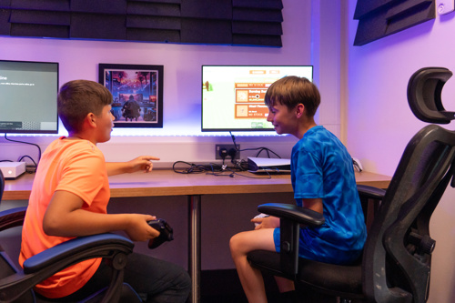 Two boys smile while playing video games together